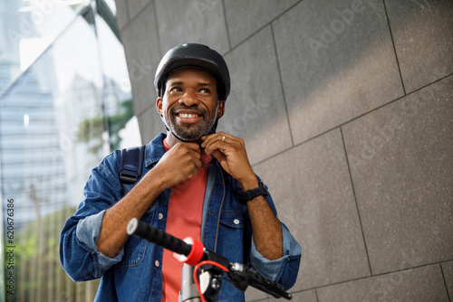 Happy man wearing helmet to ride push scooter in city photo