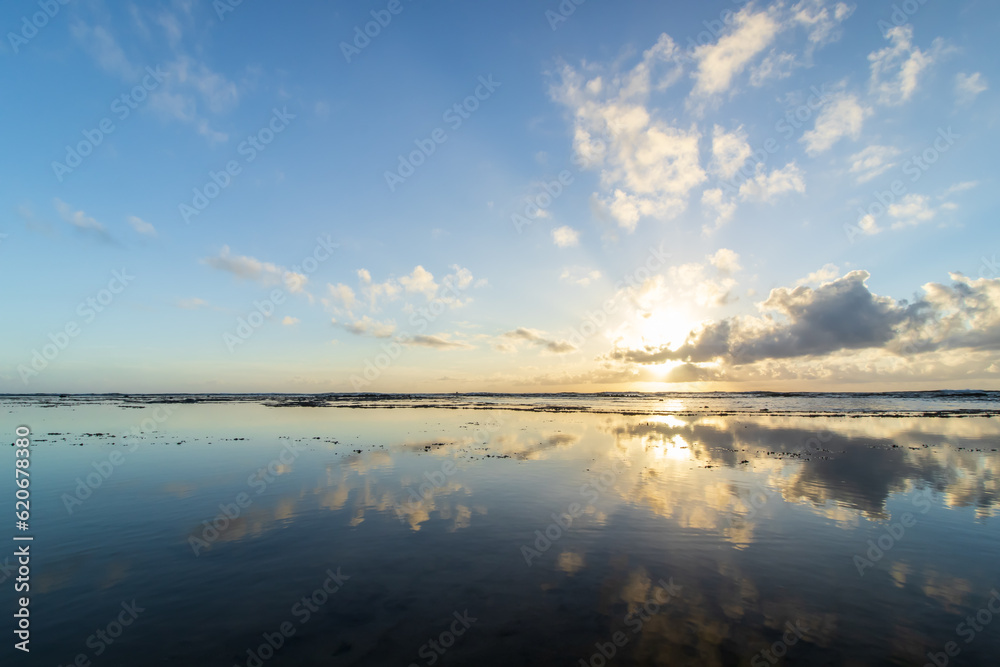beautiful sunrise at mirrored beach . Reflections in the water. the water reflects the sun, sky and clouds