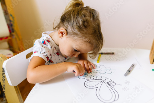 Little girl concentrates as she colors