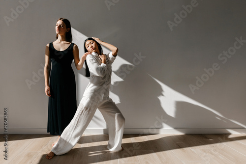 Confident ballerina dancing with partner in studio