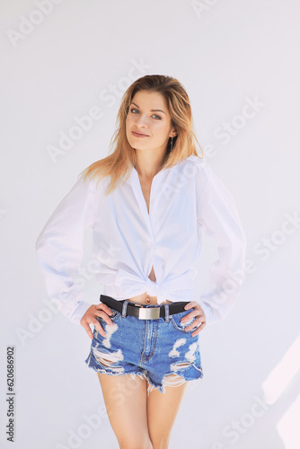 Portrait of young beautiful trendy caucasian woman in white shirt and denim shorts. Natural beauty, healthu lifestyle, cosmetology, fashion  photo