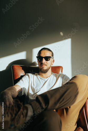 Serious trendy man sitting in a leather couch photo