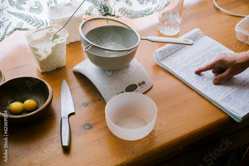 Kitchen scales, broken eggs, cream, a knife, and a recipe notebook