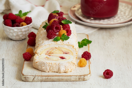 Obraz na płótnie Meringue roll with butter cream and raspberry curd, decorated with berries on a light background. w salonie
