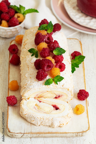 Obraz na płótnie Meringue roll with butter cream and raspberry curd, decorated with berries on a light background. w salonie