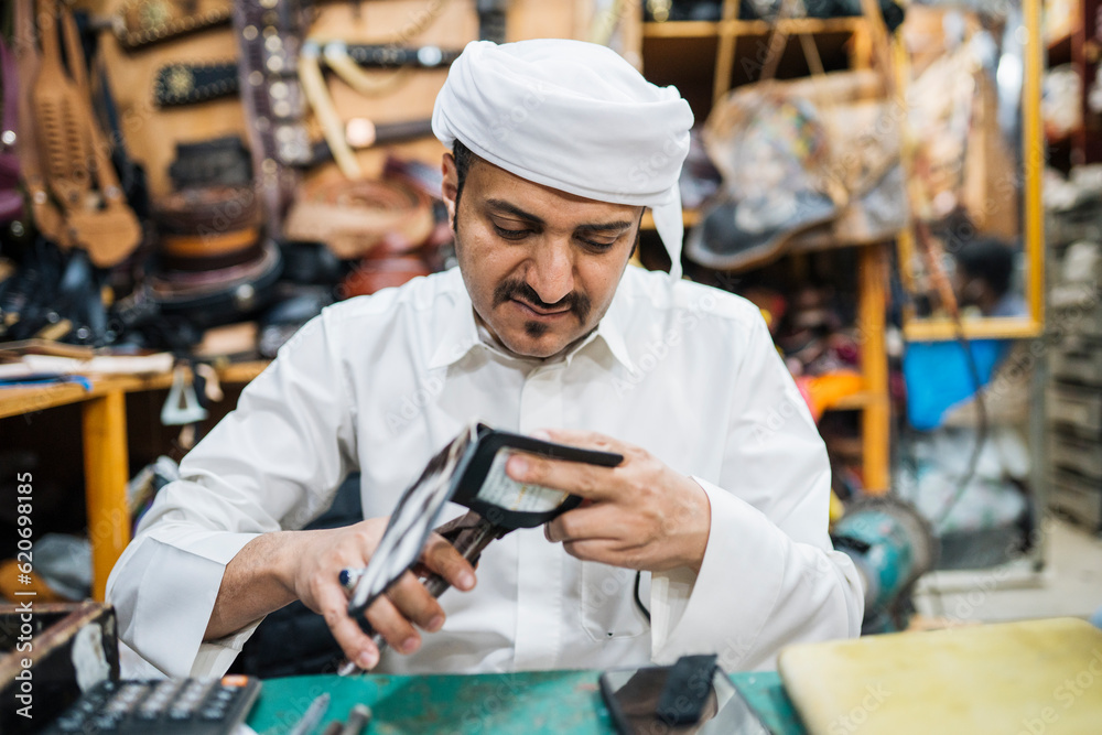 Concentrated man making leather purse Concentrated man making leather purse