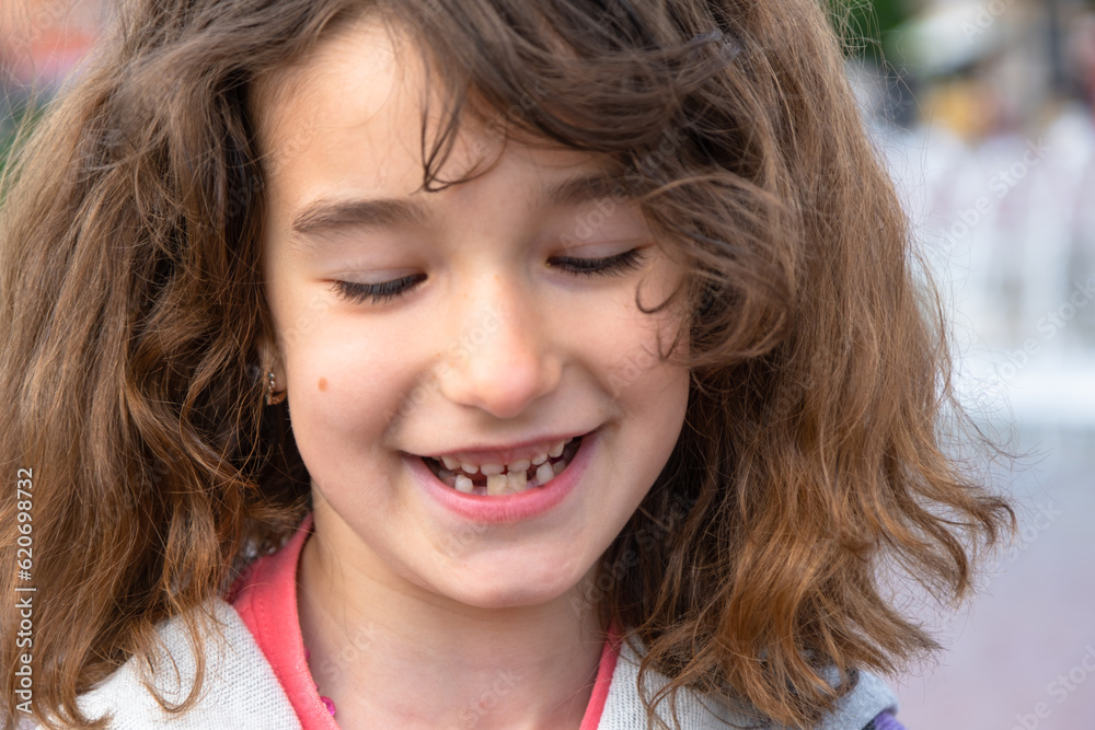 Toothless happy smile of a girl with a fallen lower milk tooth closeup
