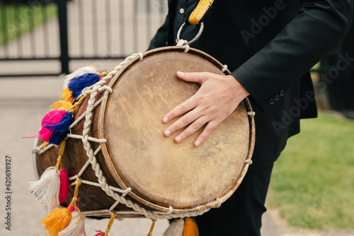 Close-up of a leather drum on a musician's neck. A street musician with a musical instrument in the form of a drum plays a rhythm. Festive musical accompaniment in the form of a rhythm on a drum
