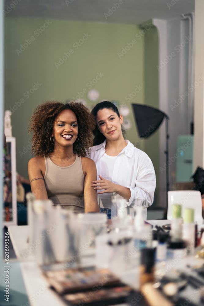 Make-up artist and model watching the make-up done in the mirror Make-up artist and model watching the make-up done in the mirror