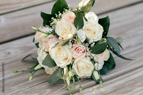 Wedding bouquet of white and pink roses on a wooden bench. Beautiful bridal bouquet of roses close-up. Traditional wedding accessory in the form of a bridal bouquet © halcon1