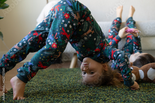 girl in pajamas stands on her head on the carpet