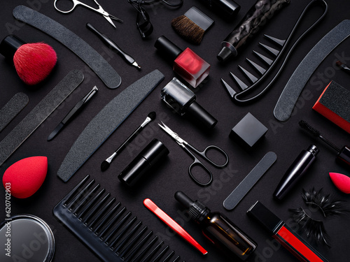 A monochrome moody and stylish photo of hair, beauty and manicure tools on a black background with red accents . Beauty procedures at home or salon visiting. Wellbeing, self treatment concept.