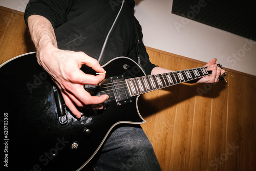 Crop man playing electric guitar during rehearsal