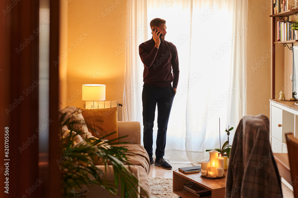 © Ivan Gener/Stocksy - Man talking on his phone in his living room