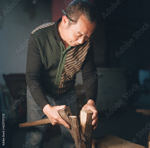 Carpenter uses an axe to chop wood
