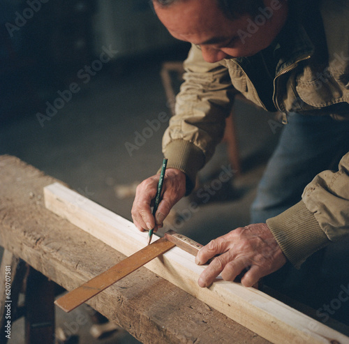 The carpenter drew lines on the stool for the wood
