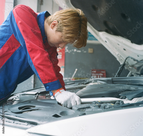 The young repairman is repairing the car