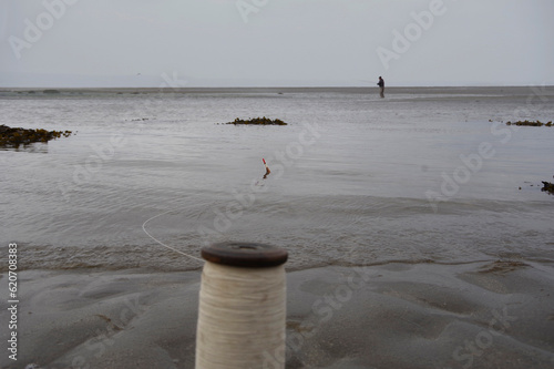 Fishing with yarn and a homemade float with  fisherman in background