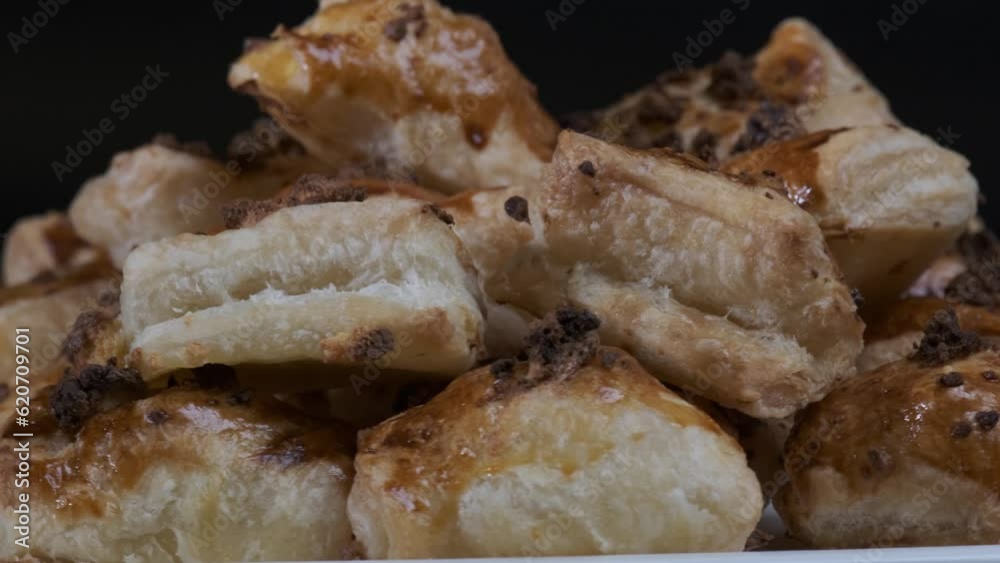 Baked puff pastry with toppings. Puffs with cheese on white plate rotating in front of camera Baked puff pastry with toppings. Puffs with cheese on white plate rotating in front of camera