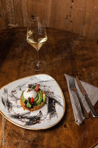 Raw salmon, avocado purple onion salad served in culinary ring on black plate. Wooden background photo