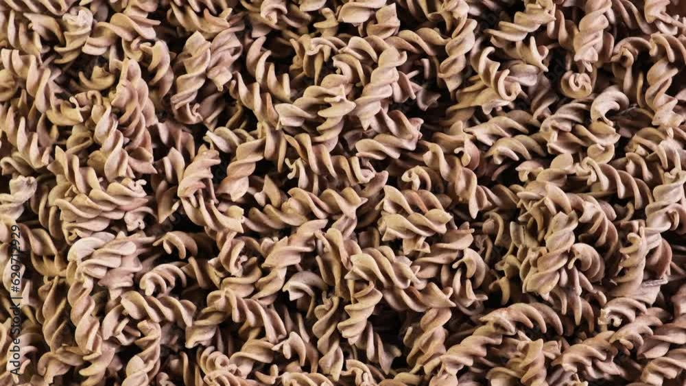 Pasta di Lino. Flaxseed gluten free pasta is rich in fiber, iron, B vitamins and Omega-3. Fusilli made from flax and corn flour. Low glycemic index food. Video 4K, counterclockwise rotation.