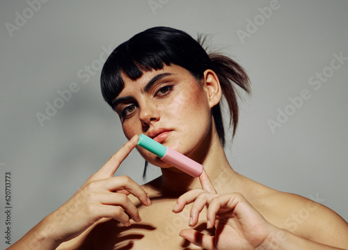 Young model showcasing new lipstick over grey background photo