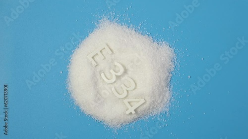 Food additive E 334. Powder. Tartaric acid is a white, crystalline organic acid that occurs naturally in many fruits, most notably in grapes, but also in bananas, tamarinds, and citrus. photo
