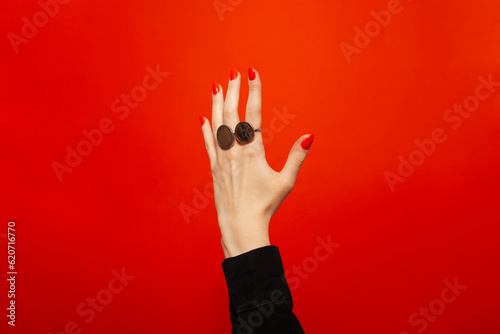 Hand with red nails with rings made of coins photo
