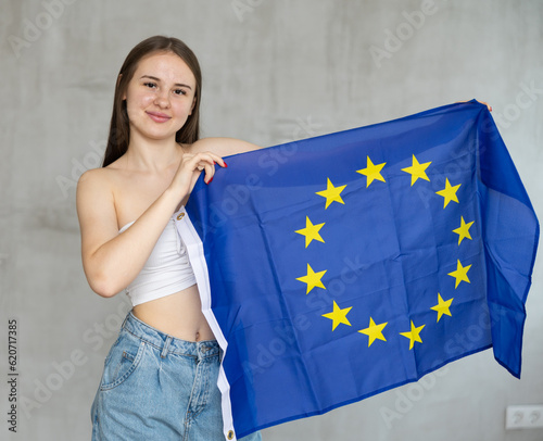 Young smiling woman posing with European Union flag in studio