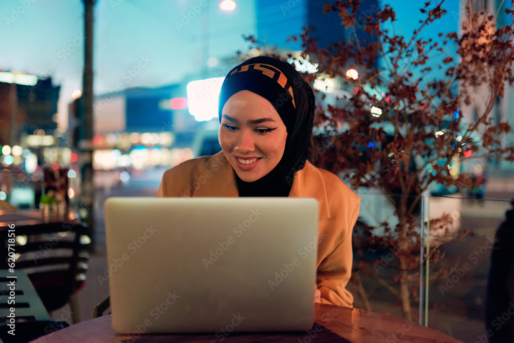 In the enchanting ambiance of a nocturnal cityscape, a hijab-clad girl engrossed in her laptop creates a mesmerizing image, embodying the fusion of technology, empowerment, and the vibrant urban In the enchanting ambiance of a nocturnal cityscape, a hijab-clad girl engrossed in her laptop creates a mesmerizing image, embodying the fusion of technology, empowerment, and the vibrant urban