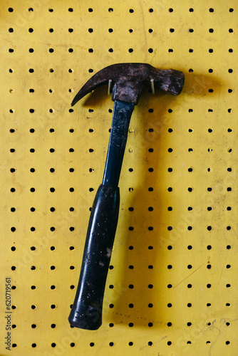 Hardware hammer hanging in Garage workshop on Yellow peg board  photo