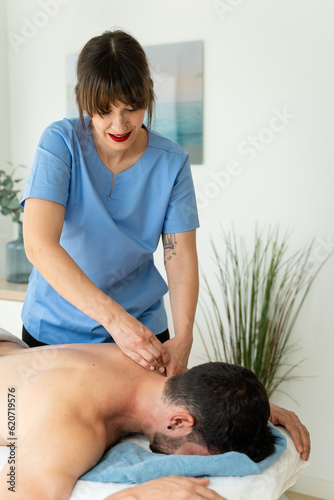 Female masseuse optimistically attending to a pacient lying down. photo