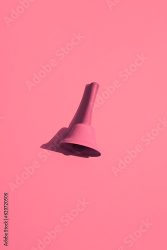 A pink bell on a pink background. Monochromatic composition photo