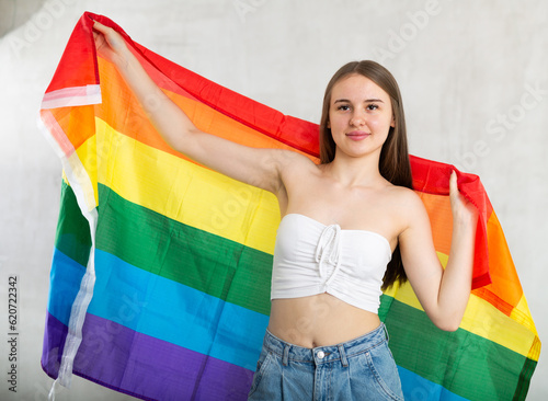 Young smiling woman posing with LGBT flag in studio