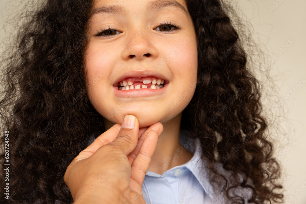 Little girl showing her missing tooth to an unrecognizable woman Little girl showing her missing tooth to an unrecognizable woman