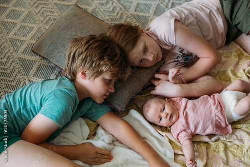 Older siblings with baby lying down