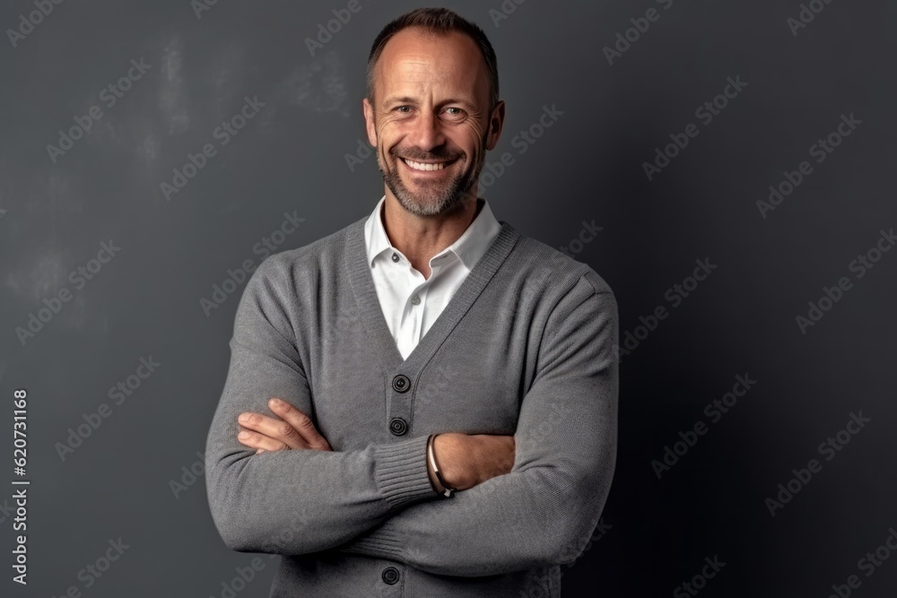 Portrait of a smiling mature businessman standing with arms crossed against grey background Portrait of a smiling mature businessman standing with arms crossed against grey background