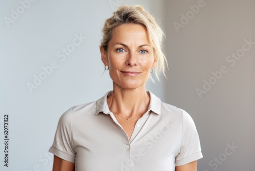 Portrait of smiling mature businesswoman standing against grey wall at office © Eber Braun