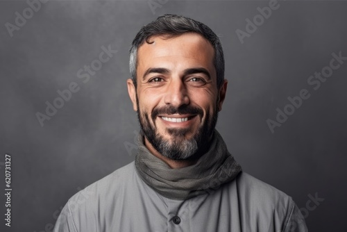 Portrait of a smiling bearded man in a gray jacket and scarf.