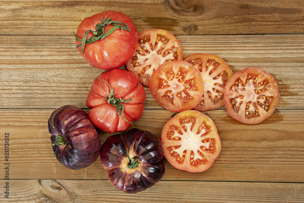 An image of tomatoes of all kinds on an unvarnished wooden table along