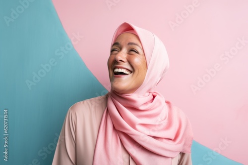 Obraz na płótnie Portrait of a young muslim woman laughing against blue and pink background w salonie