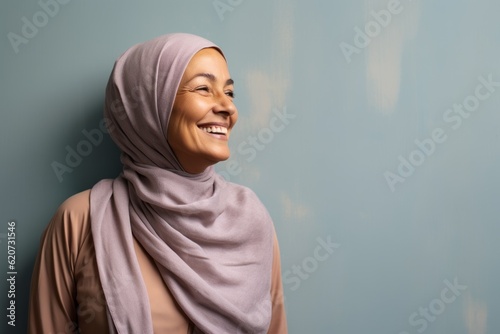 Obraz na płótnie Portrait of a smiling young muslim woman wearing hijab against blue wall w salonie