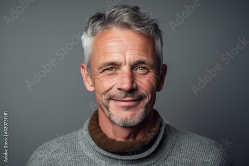 Portrait of a handsome mature man with grey hair wearing a gray sweater.