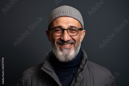 Portrait of a bearded Indian man wearing a grey beanie and glasses