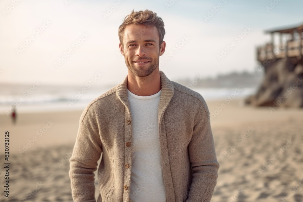 Portrait of handsome young man standing on the beach and looking at camera Portrait of handsome young man standing on the beach and looking at camera