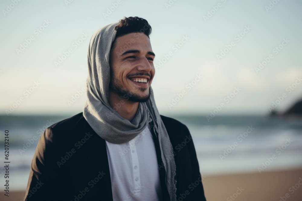 Portrait of smiling young man with headscarf standing on beach