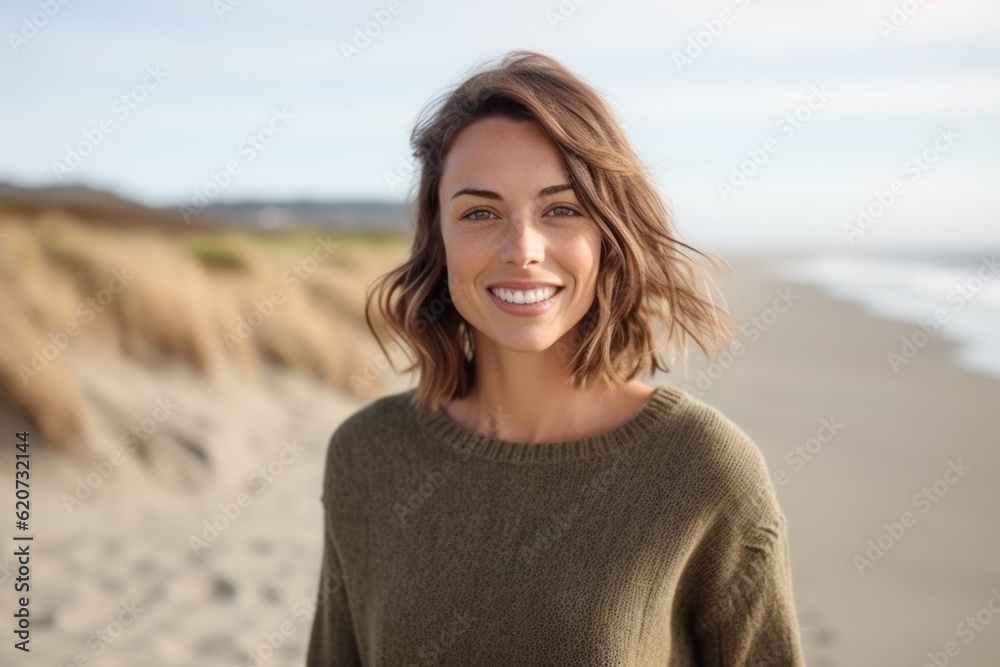Portrait of a beautiful young woman smiling at camera on the beach Portrait of a beautiful young woman smiling at camera on the beach