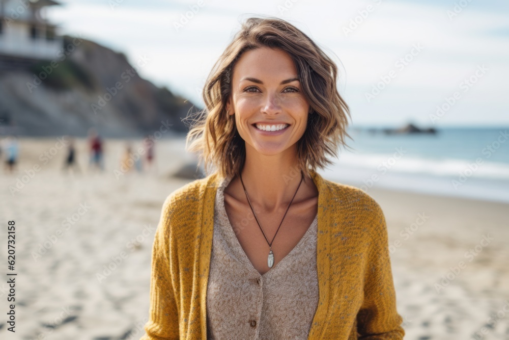 Portrait of beautiful young woman smiling at camera while standing on beach Portrait of beautiful young woman smiling at camera while standing on beach