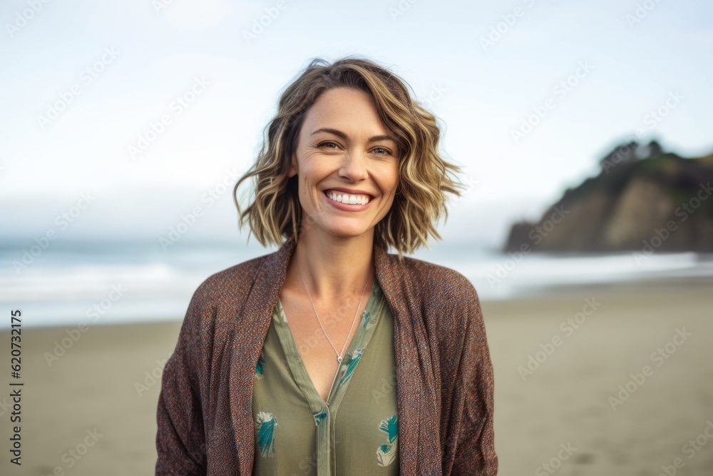 Portrait of smiling woman standing on beach at the beach in the sunshine Portrait of smiling woman standing on beach at the beach in the sunshine