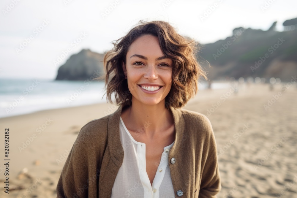 Portrait of a smiling young woman standing on the beach at sunset Portrait of a smiling young woman standing on the beach at sunset